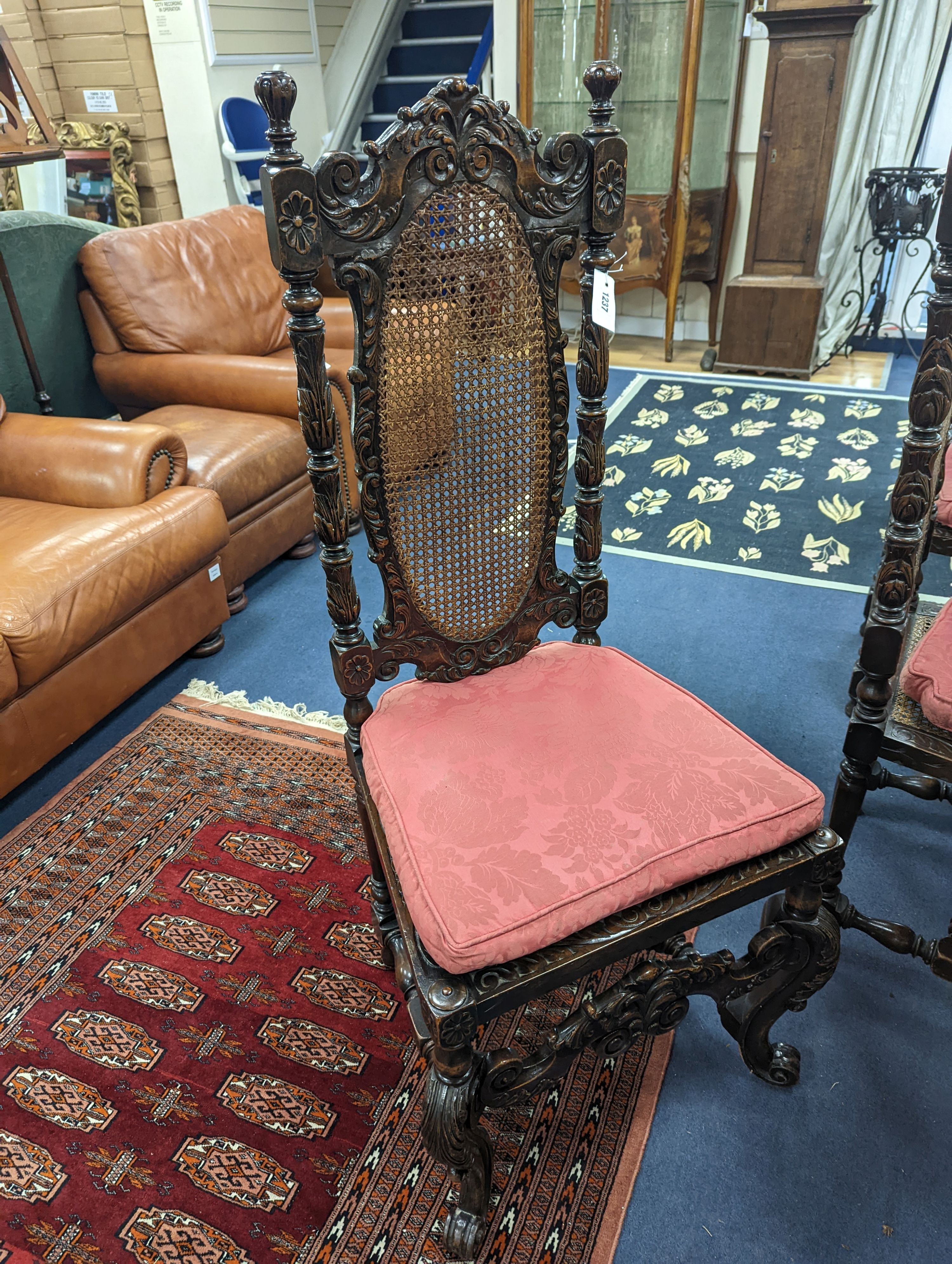 A set of six Charles II style carved oak dining room chairs with caned backs and seats and squab cushion seats